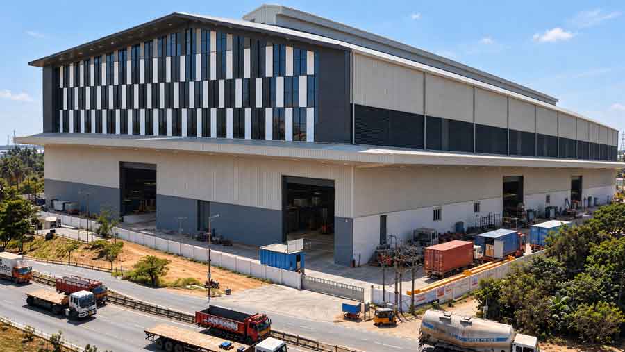 Large industrial building with a striped glazed facade and loading trucks